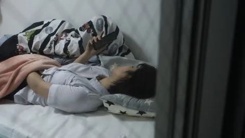 Asian Teen Uses Phone in Bedroom