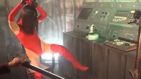 Asian woman in red bodysuit dominated by masked men