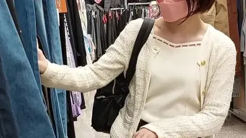 Asian teen in pink face mask kneeling in clothing store