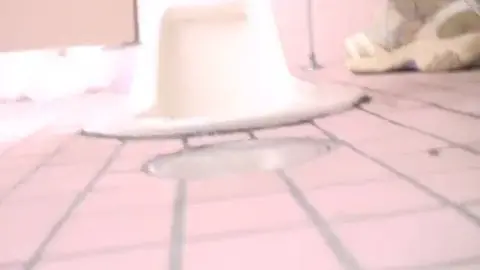 Asian Woman Urinating in Bathroom